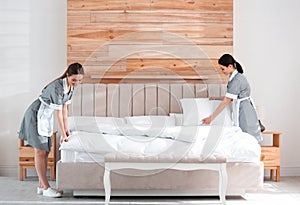 Chambermaids making bed in hotel room