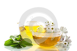 Chamomile flower tea in glass cup and teapot, on white background.