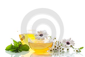 Chamomile flower tea in glass cup and teapot, on white background.