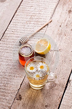 Chamomile flowers and chamomile tea. Chamomile tea in cup with flowers, honey and lemon, close-up. Seasonal treatment, alternative