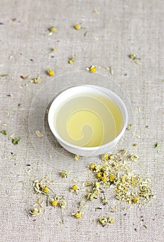 Chamomile herbal tea in chinese cup and dry herb flowers