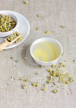 Chamomile herbal tea in chinese cup and glass jar with dry herb flowers, above overhead view