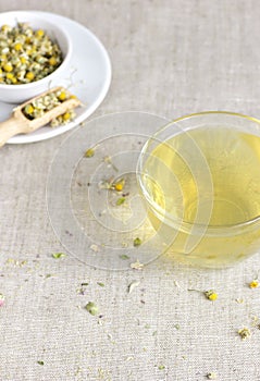 Chamomile herbal tea in glass cup and jar with dry herb flowers