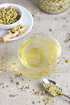 Chamomile herbal tea in glass cup and jar with dry herb flowers, above overhead view, naturopathy, natural medicine,