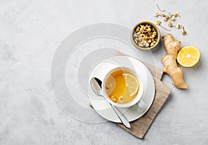 Chamomile herbal tea with lemon in a white cup on a light background with dry flowers and ginger. The concept of a healthy detox