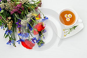Chamomile, poppy, cornflower, yarrow and other beautiful summer field flowers with cup of chamomile tea.