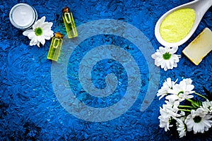 Chamomile spa cosmetics with natural herbal ingredients. Chamomile spa salt, soap, oil and cream on blue background top