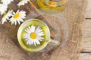 chamomile tea is a therapeutic healthy drink a cup against the background of daisies A lot of daisies on the table Copy