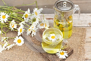 chamomile tea is a therapeutic healthy drink A teapot with a cup on a wooden background A bouquet of daisies on the