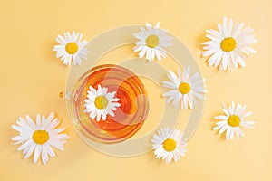 Chamomile tea in a transparent cup on a yellow background.