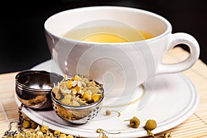 Chamomile tea in the white glass with opened tea strainer photo