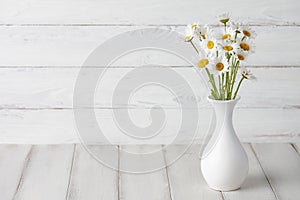 Chamomiles or daisies in white vase