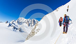 CHAMONIX, FRANCE - MARCH 19, 2016: a group of mountaineer climb a snowy peak. In background the glaciers and the summit of Mont Bl