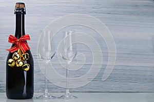 Champagne alcoholic drink, in a black bottle with Christmas decoration, next to two glass glasses, on a light gray background,