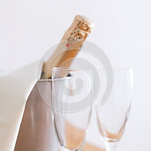 Champagne bottle in bucket and two empty glasses