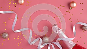 Champagne bottle with confetti stars and party streamer on pink background. Christmas or birthday celebration concept. Flat lay,