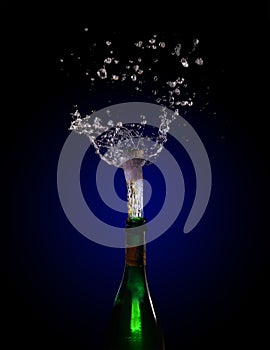 Champagne bottle explosion with cork popping splash against a da