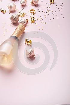 Champagne bottle, gift or present box and golden shiny sparkle star confetti on pink background. Christmas or New Year composition