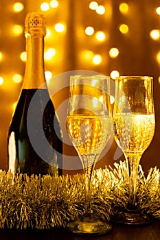 Champagne bottle with glasses of champagne on background with LED lights garland. New year and Christmas. Copy Space