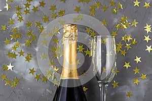 Champagne bottle and glasses with gold confetti stars. Concept for christmas, birthday or wedding