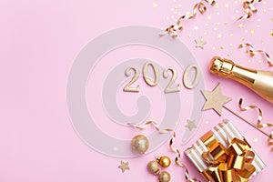 Champagne bottle, golden gift or present box, 2020 number and confetti on pink background top view.Christmas and New Year flat lay