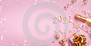 Champagne bottle, golden gift or present box, 2021 number and confetti on pink background top view. Christmas and New Year card.