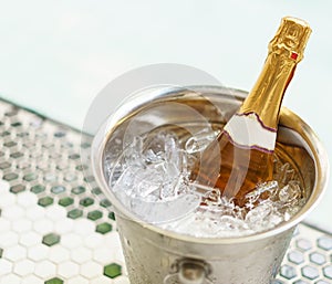 Champagne bottle in ice bucket and two glasses near jacuzzi pool