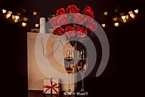 Champagne bottle, red roses in a paper bag and two wine glasses