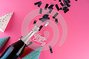 Champagne bottle with silver sparkles flat lay on pink paper background