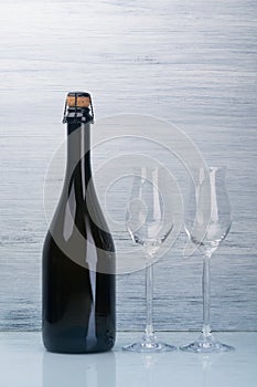 Champagne bottle and two empty glasses on a gray background