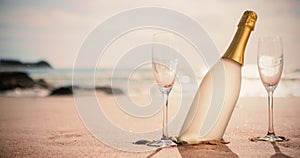 Champagne bottle and two glasses on sand