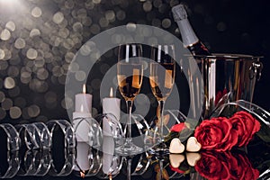 Champagne bottle with two wine glasses, chocolates and bouquet of roses