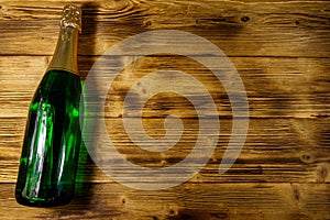 Champagne bottle on wooden background. Top view, copy space