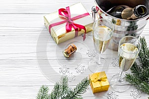 Champagne for celebrate new year. Glasses, bottle in bucket, spruce branch on white wooden background copyspace