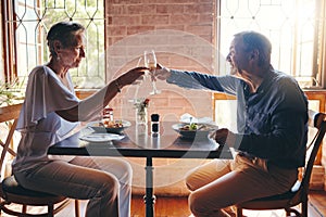 Champagne, celebration and senior couple giving toast for love, anniversary or birthday with lunch at a restaurant