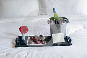 Champagne and chocolate strawberries on bed