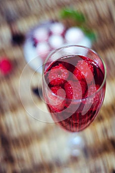 Champagne cocktails with raspberries for a romantic evening on a wooden table. Pink liquid color, glasses with bubbles