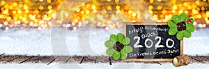 Champagne cork and blackboard with german greeting frohes neues jahr 2020 english translation: happy new year 2020  wooden