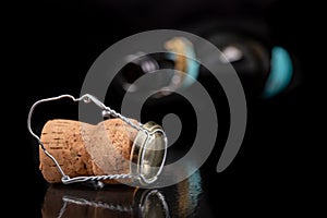 Champagne cork on a dark table. Metal basket and bottle stopper with alcoholic liquor