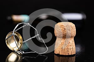 Champagne cork on a dark table. Metal basket and bottle stopper with alcoholic liquor