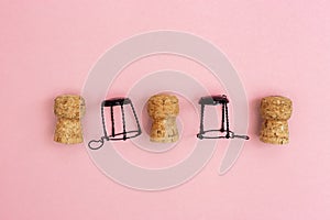 Champagne corks and muselets on pink paper background with copy space. Close up used wooden stoppers