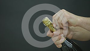 Champagne explosion. Man hand opening champagne bottle closeup. Sparkling Wine over Holiday Bokeh Blinking Background