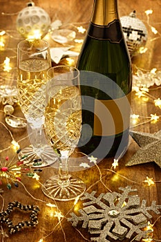 Champagne flutes and bottle with christmas lights, baubles and silver stars decorations