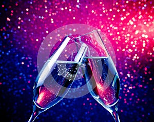 Champagne flutes with bubbles on blue tint light bokeh background