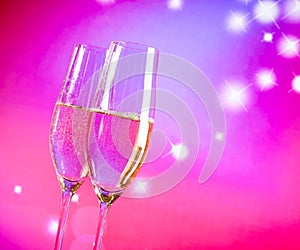 Champagne flutes with gold bubbles on blue and violet tint light background