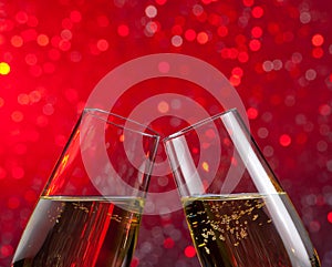 Champagne flutes with gold bubbles on red light bokeh background