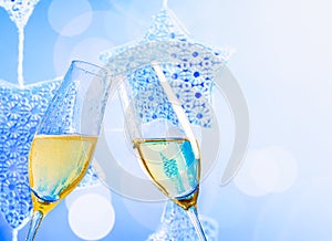 Champagne flutes with golden bubbles on blue christmas lights decoration background