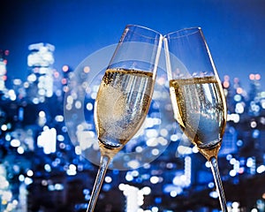 Champagne flutes with golden bubbles on blue city night lights background