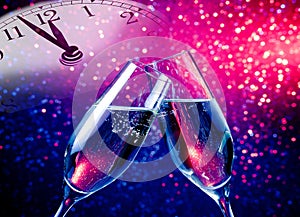 Champagne flutes with golden bubbles on blue and purple violet light bokeh background