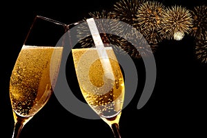 Champagne flutes with golden bubbles make cheers with fireworks sparkle and black background